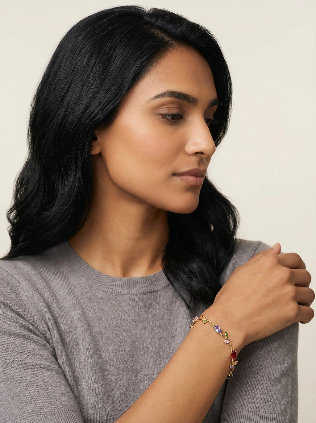 Aurum & Isle Flora vine gold bracelet with floral-link design, paired with grey cashmere sweater.