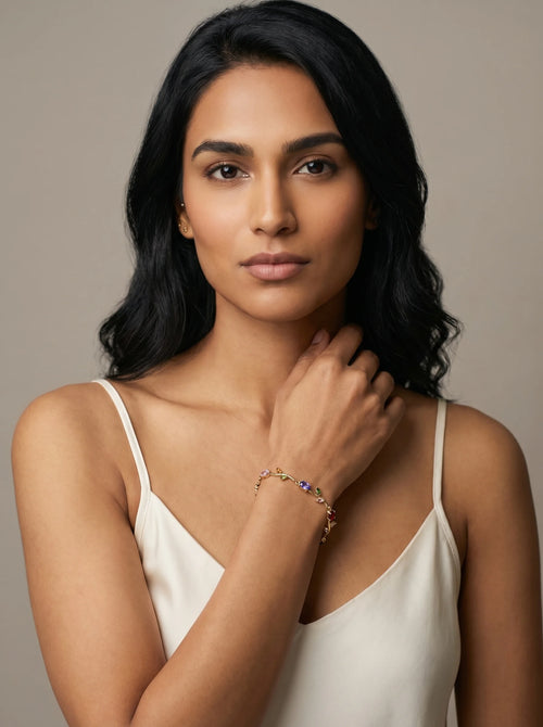 Aurum & Isle Flora vine bracelet in gold with multicolour stones, worn with cream slip dress.