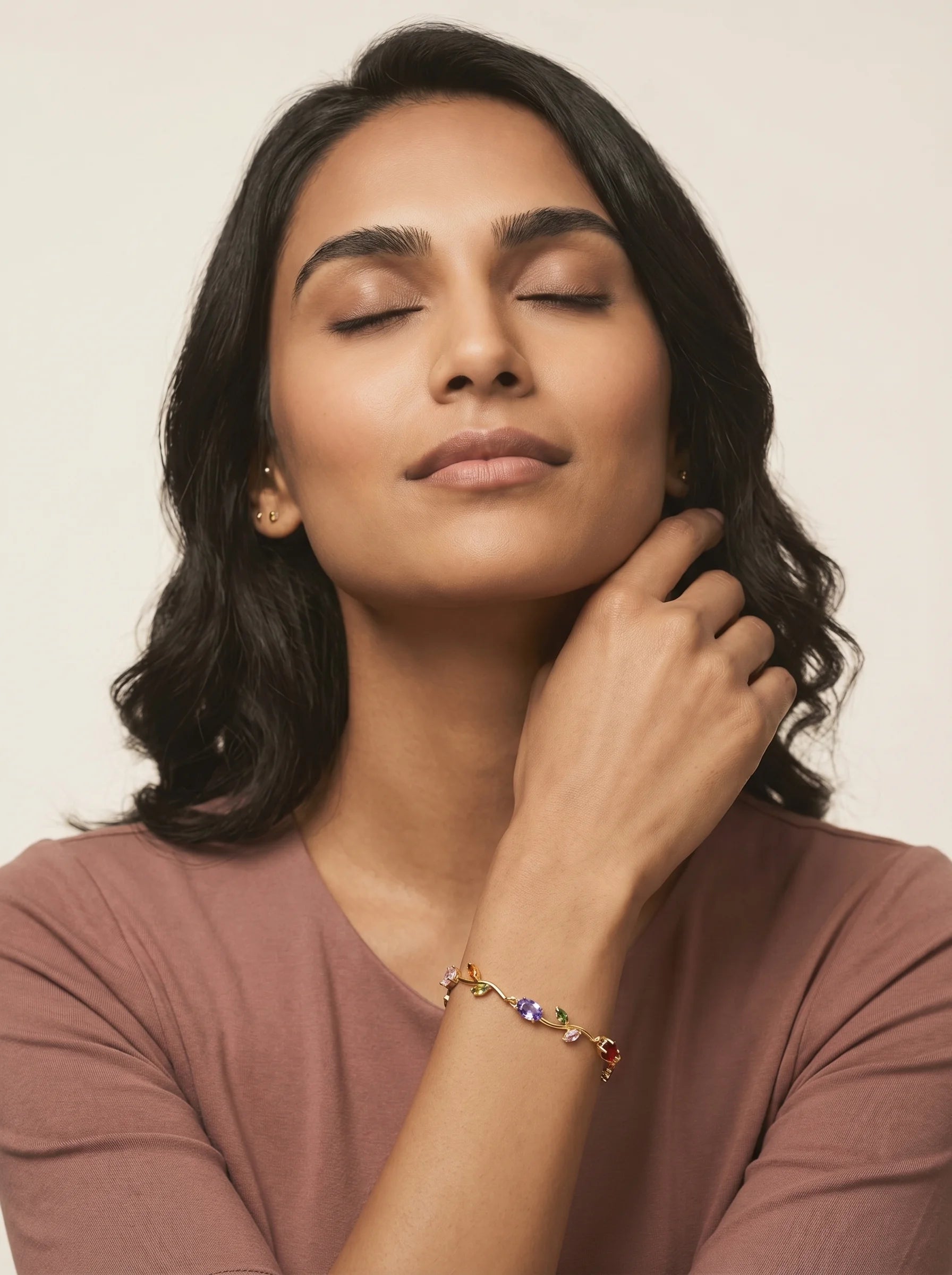 Aurum & Isle Flora vine gold bracelet on model in dusty rose top, eyes closed — soft editorial styling.