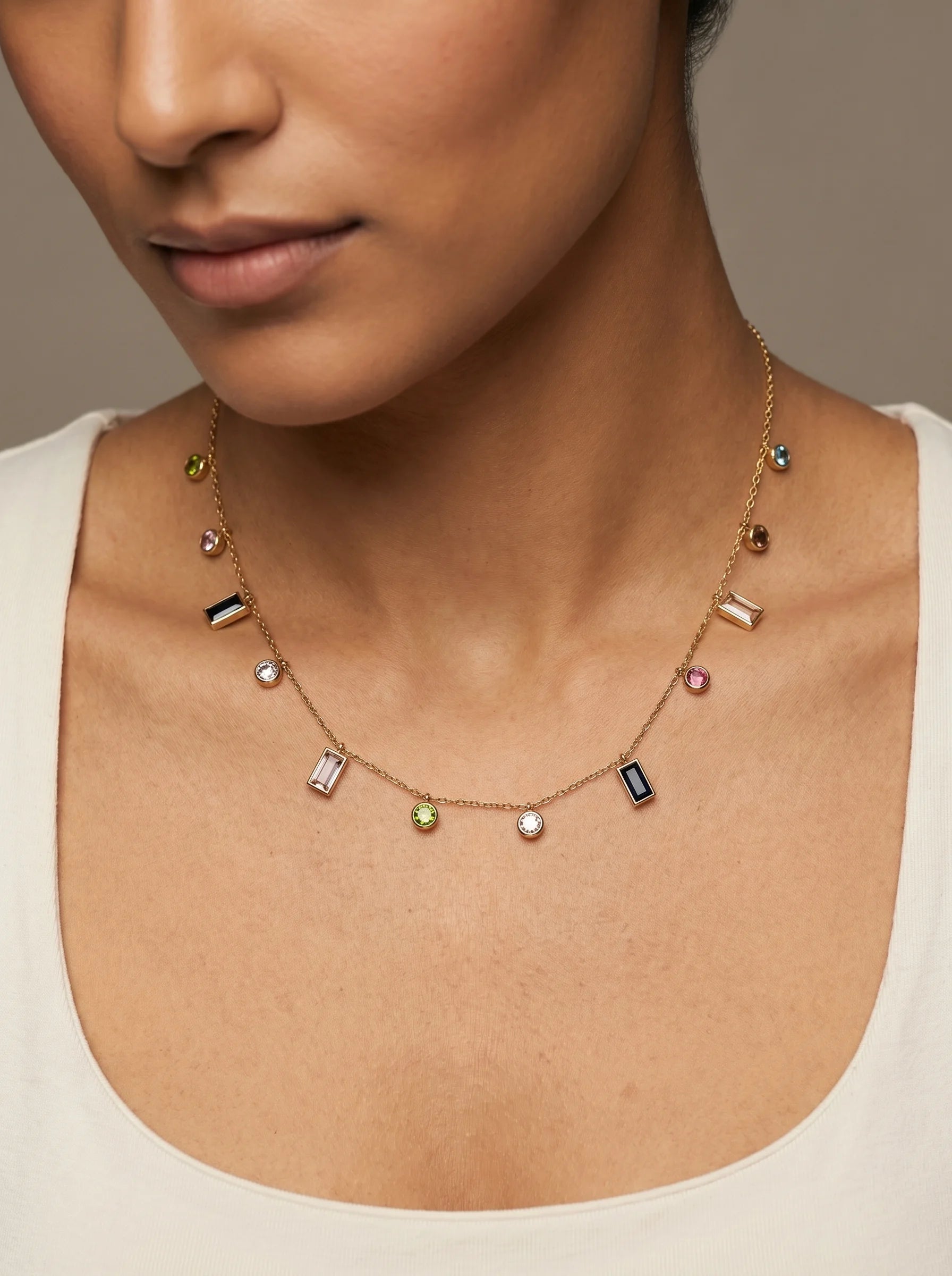 Close-up of Aurum & Isle Mosaic charm necklace — gold chain with mixed-cut baguette, round and bezel charms.