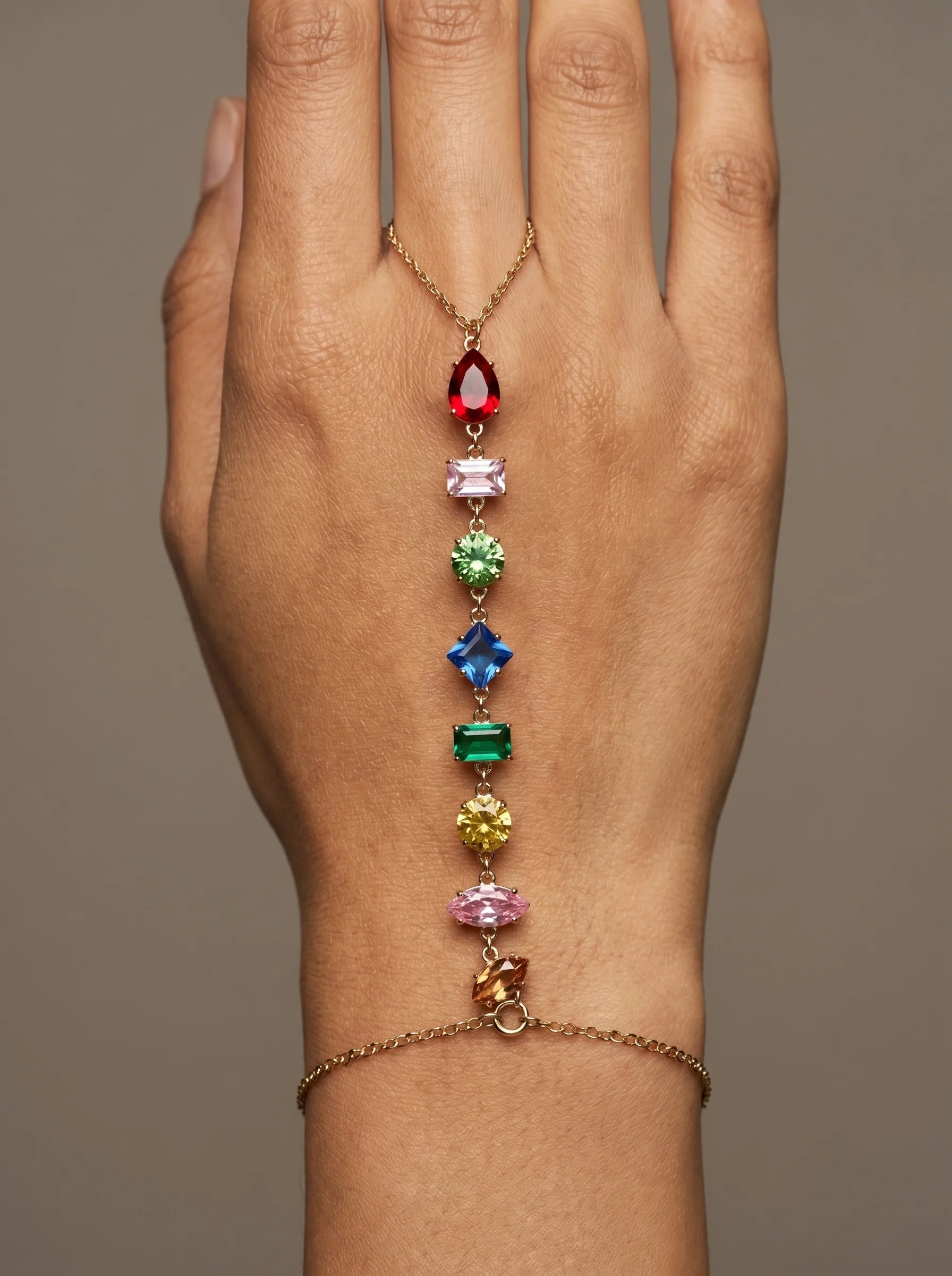Close-up of Aurum & Isle Prism hand harness — gold chain from ring to bracelet with pear, square and round cut stones.