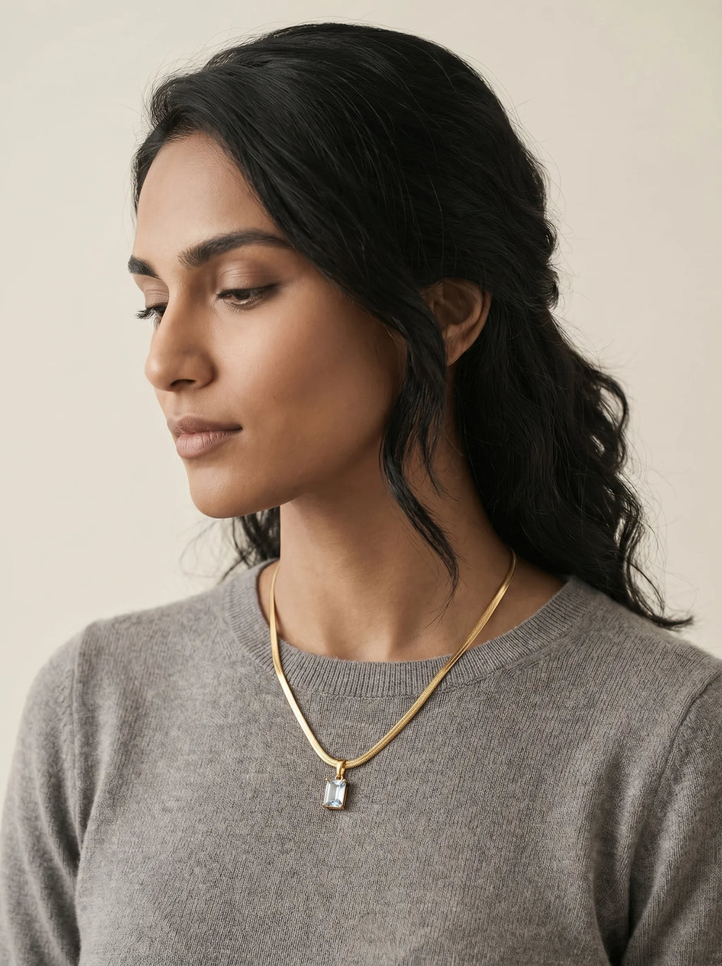 Aurum & Isle Soleil gold snake chain pendant styled with grey cashmere — everyday anti-tarnish jewellery.