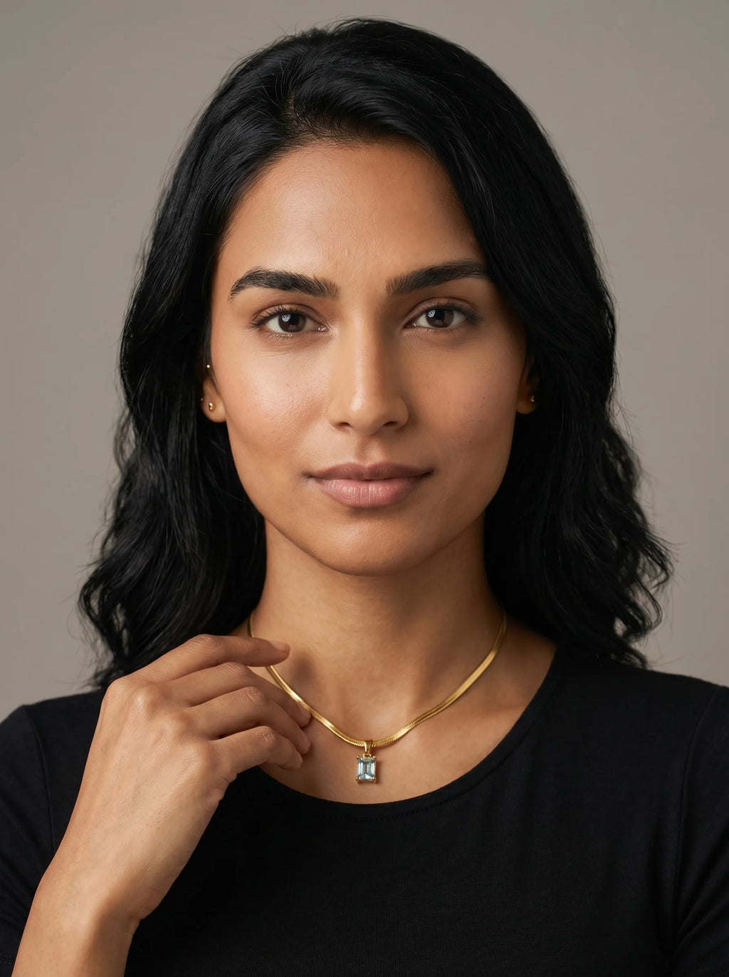 Aurum & Isle Soleil snake chain pendant in gold with blue stone, worn with black top — anti-tarnish nickel-free necklace.