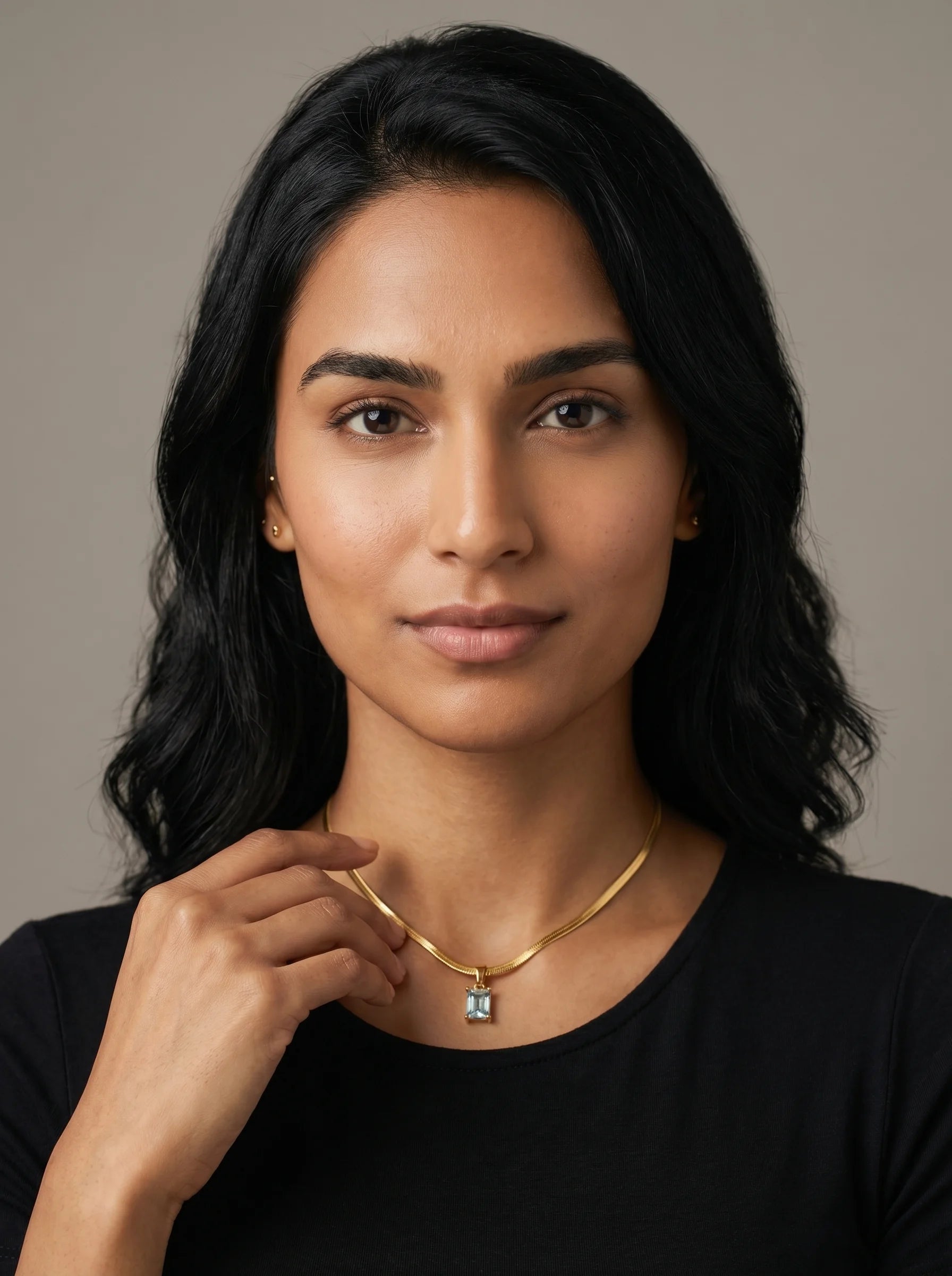 Aurum & Isle Soleil snake chain pendant in gold with blue stone, worn with black top — anti-tarnish nickel-free necklace.