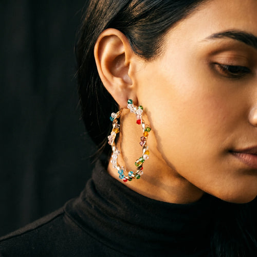Aria twisted gold hoop with jewel-tone crystal beads worn on model in black turtleneck — close-up