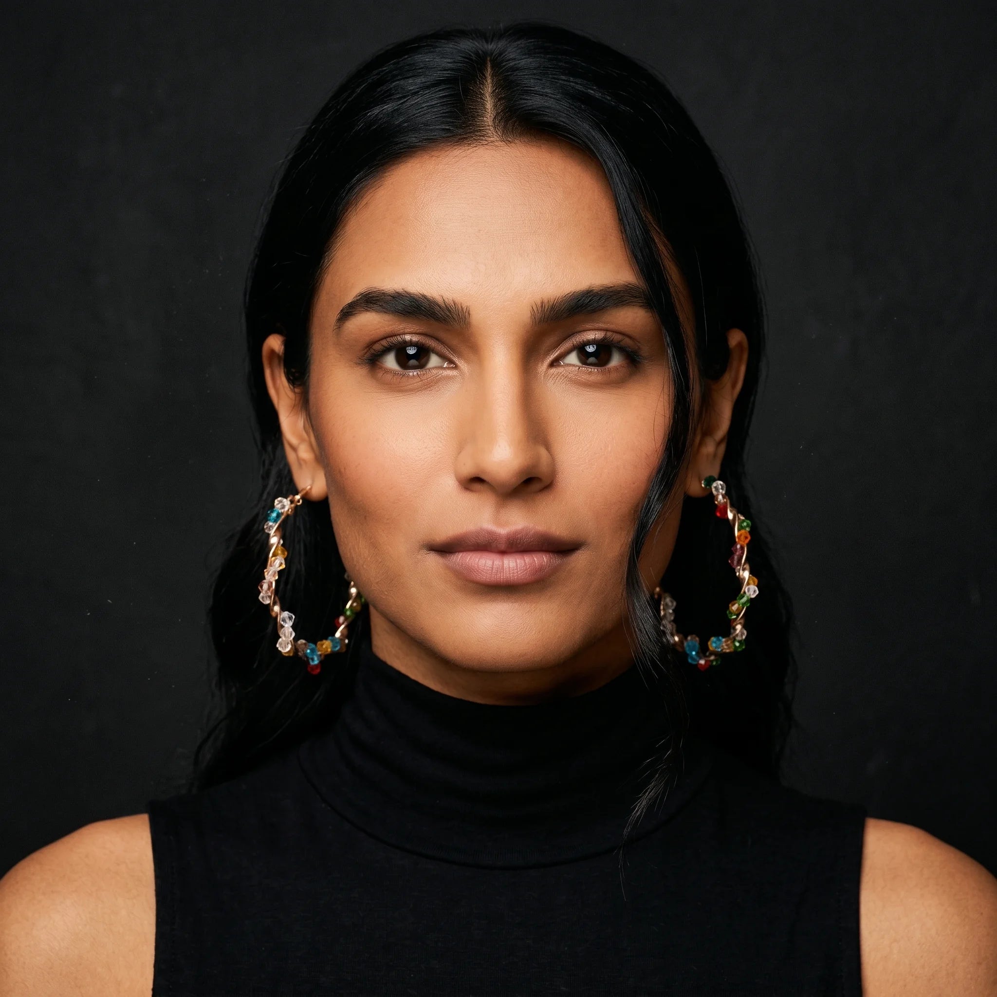 Aria twisted gold hoops with multicolour crystal beads worn front-facing with black turtleneck
