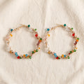 Aria twisted gold hoops wrapped in multicolour bicone crystal beads on cream linen — Aurum & Isle