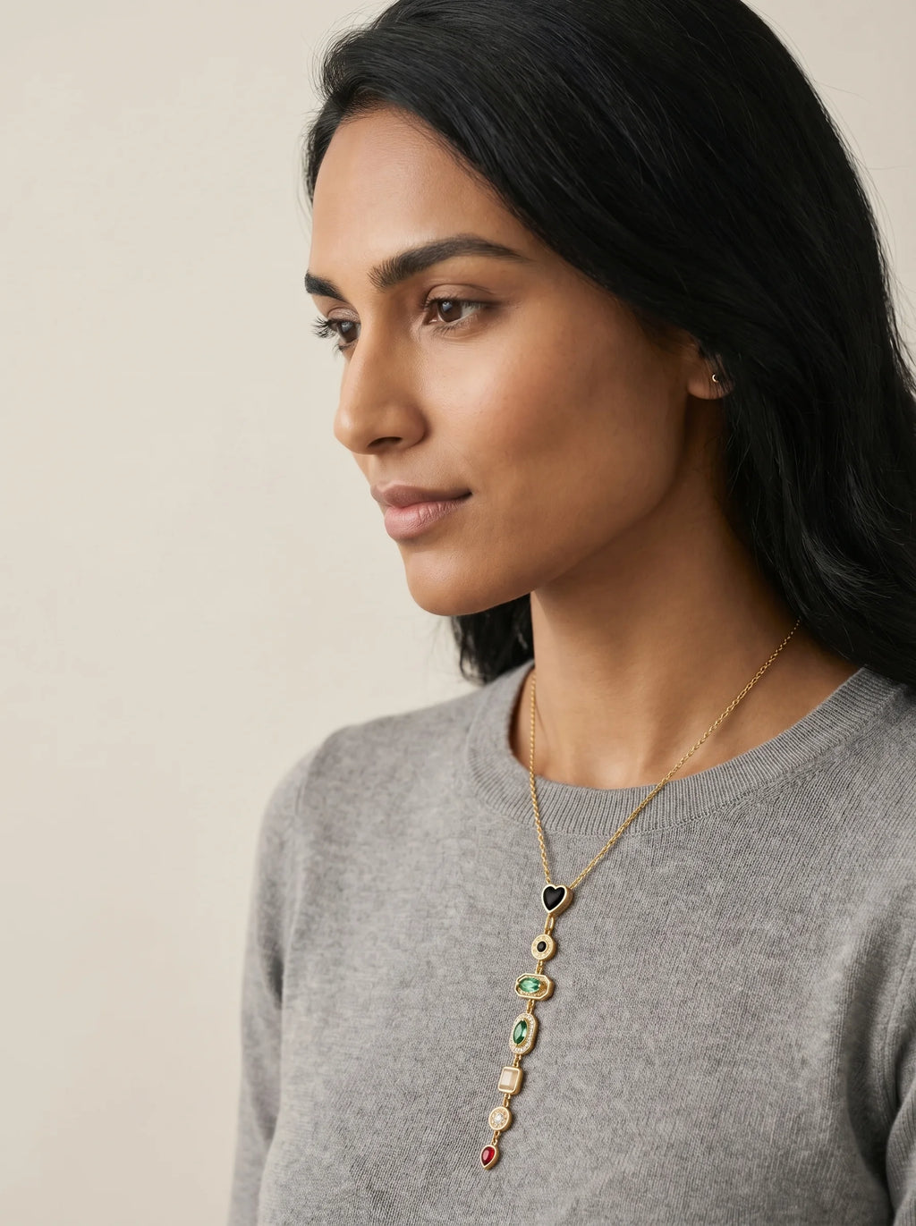 Aurum & Isle Éclat Y-drop necklace in gold with layered gemstones, styled with grey cashmere.