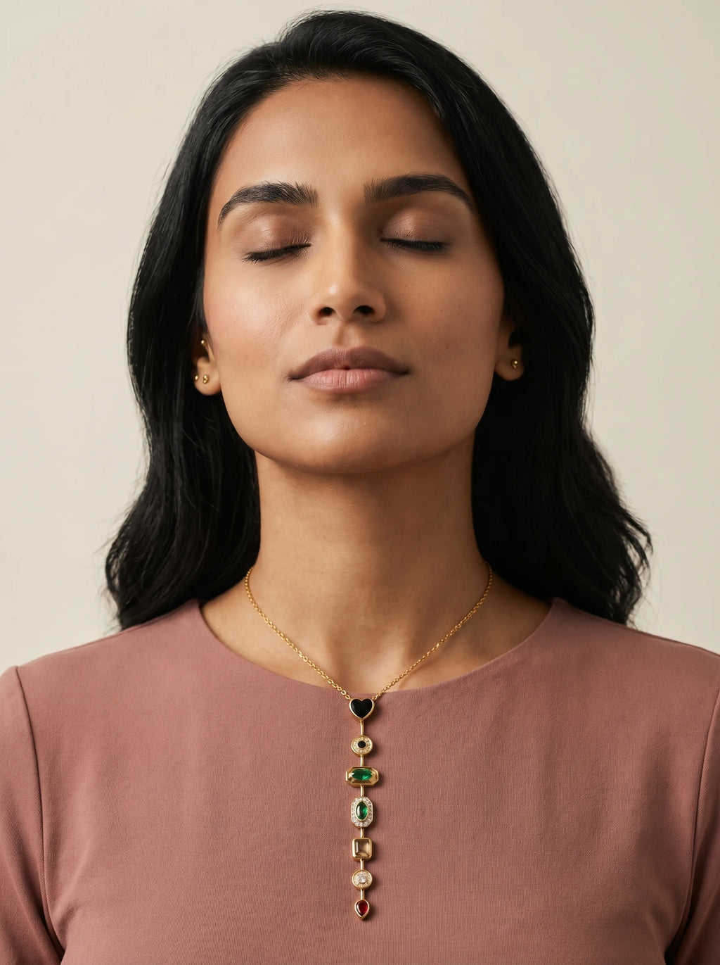 Aurum & Isle Éclat gold Y-drop necklace on model in dusty rose top, eyes closed — editorial moment.