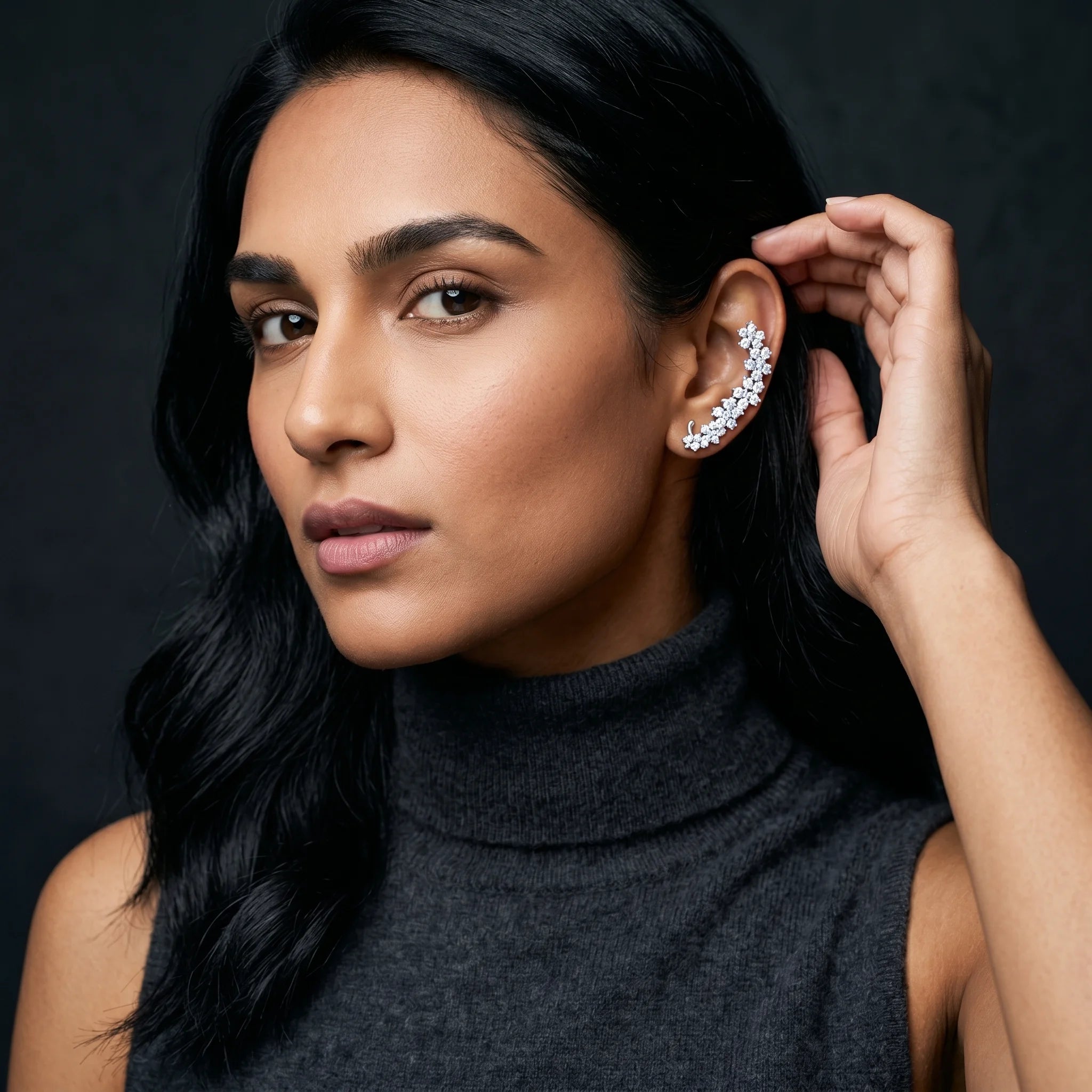 Indu silver floret climber ear cuff worn on model with charcoal turtleneck — close-up with hand near ear
