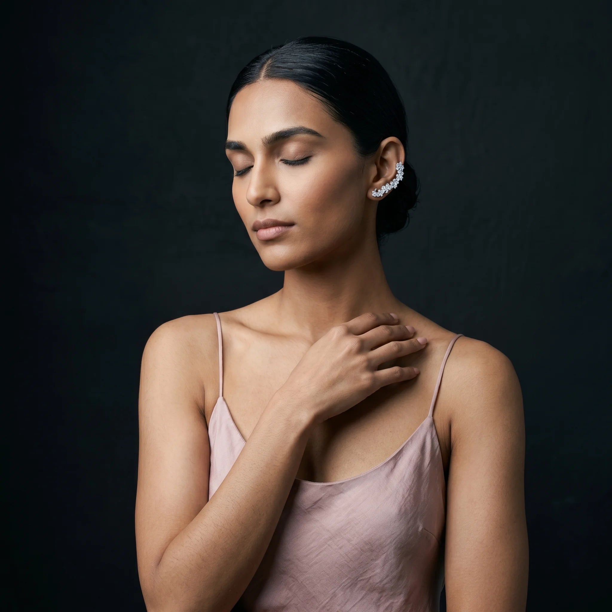 Indu silver ear cuff with eyes closed and hand at collarbone — dusty rose silk slip
