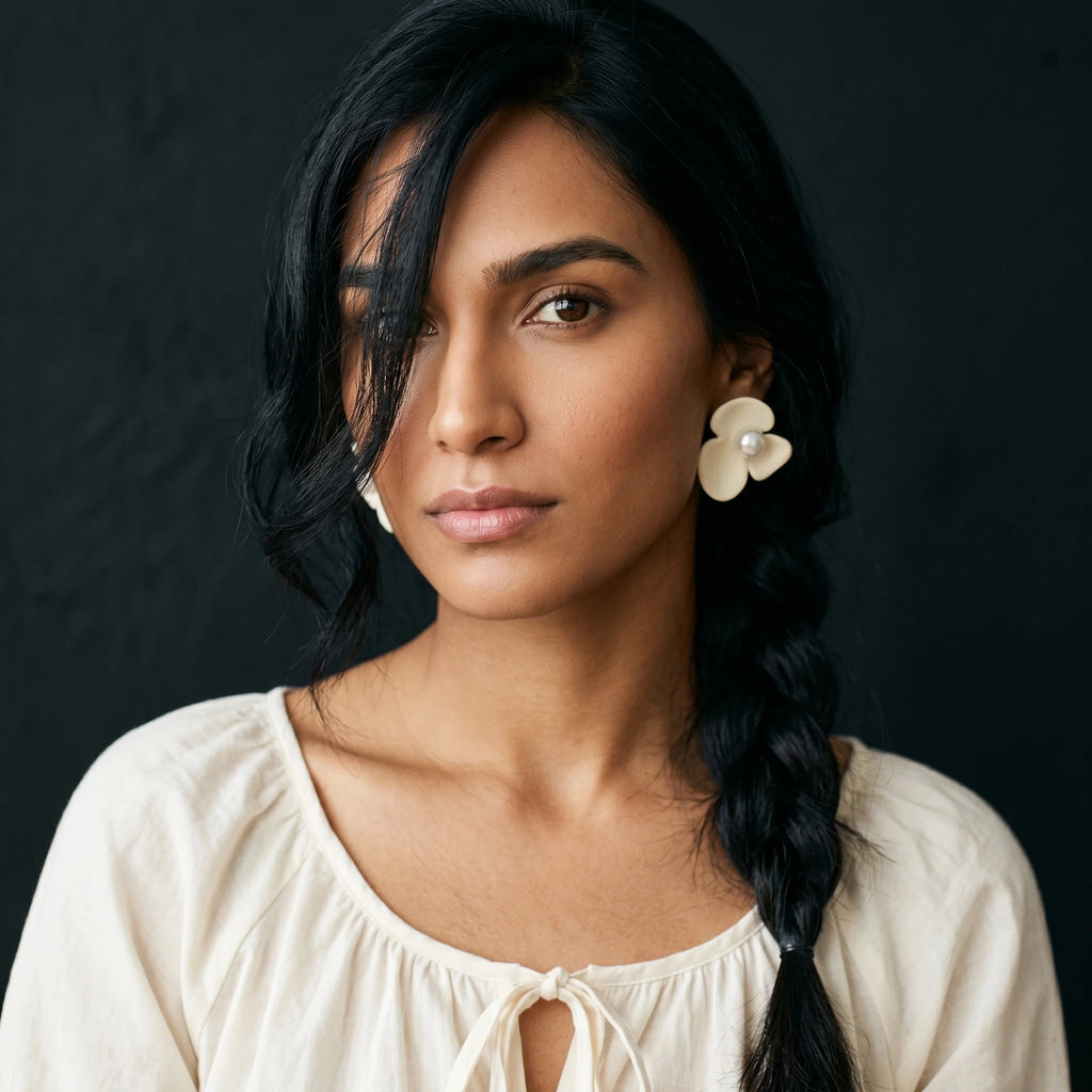 Kalika cream flower clip-ons worn with cream peasant top and side braid — soft editorial portrait