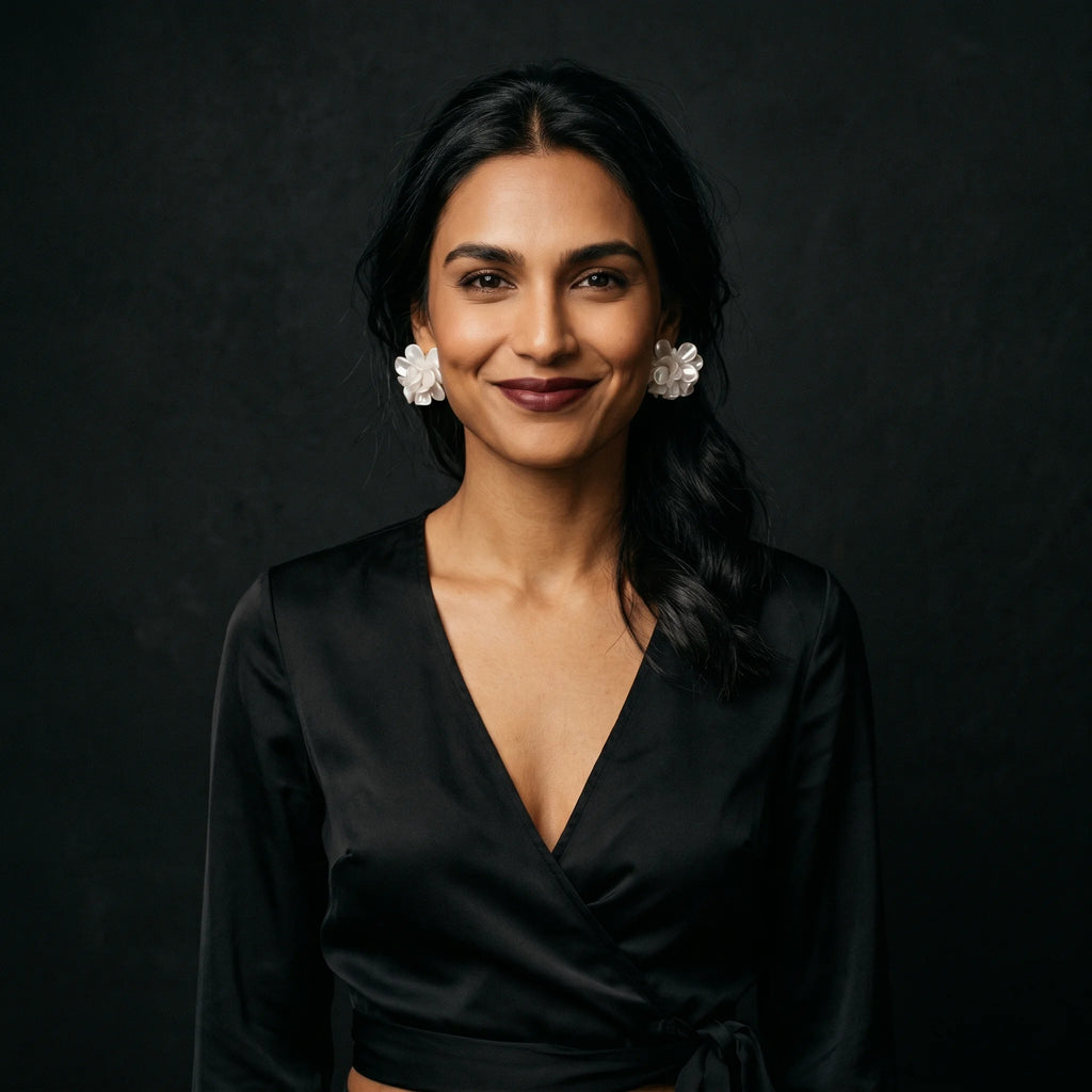 Malati white pearlescent flower cluster studs worn with black satin wrap — front-facing soft smile