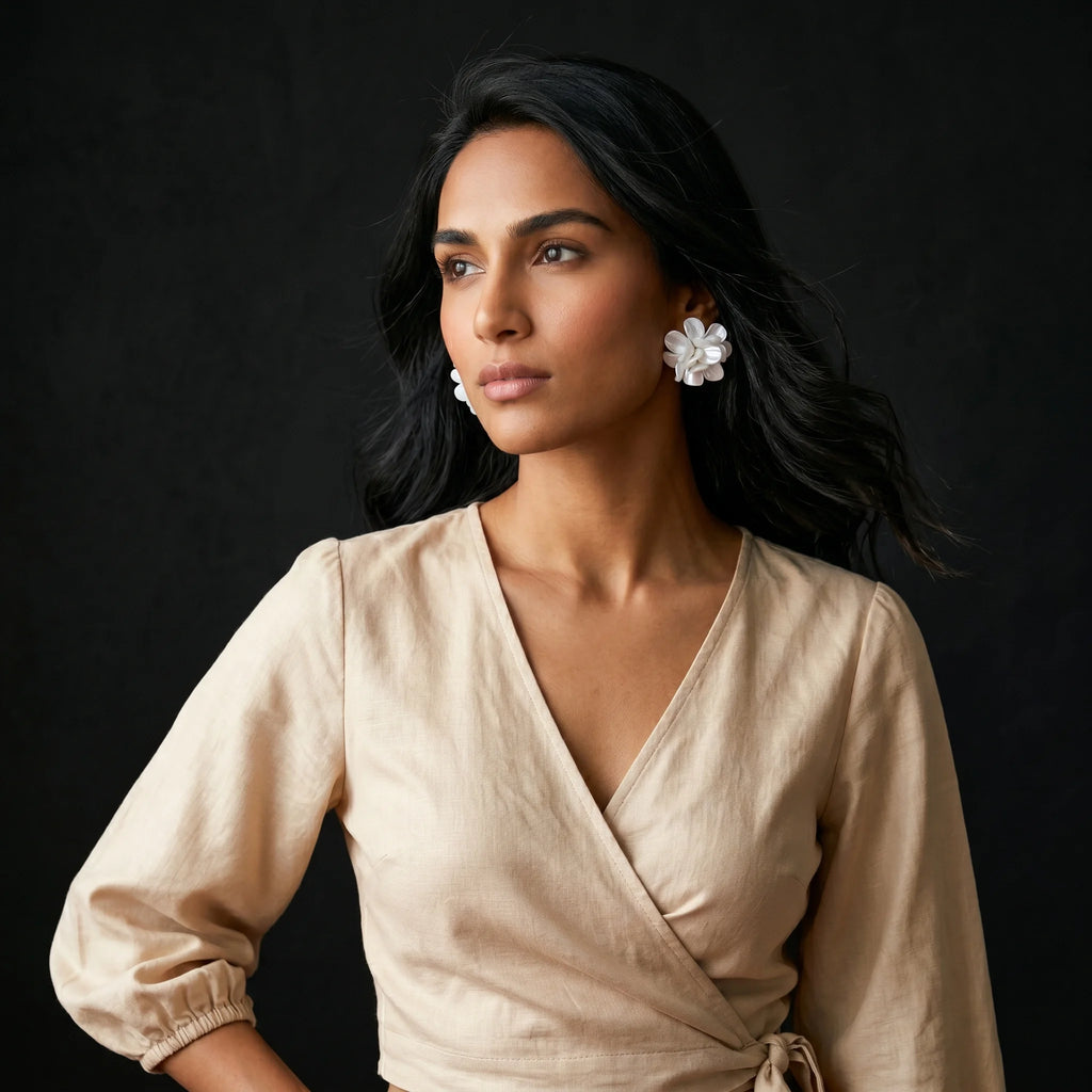 Malati white flower cluster studs worn with beige linen wrap dress — three-quarter editorial portrait