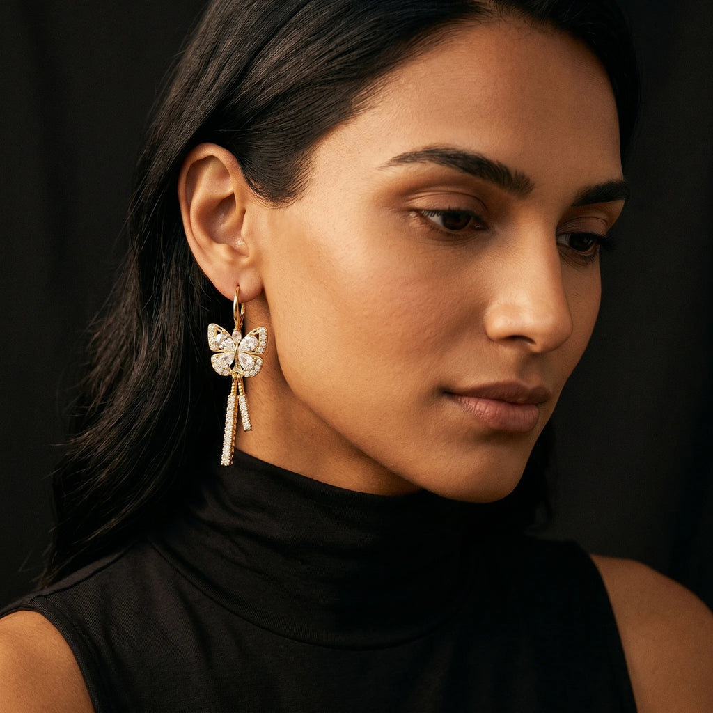 Mira gold butterfly earring with pavé tassel drop worn on model in black turtleneck — close-up