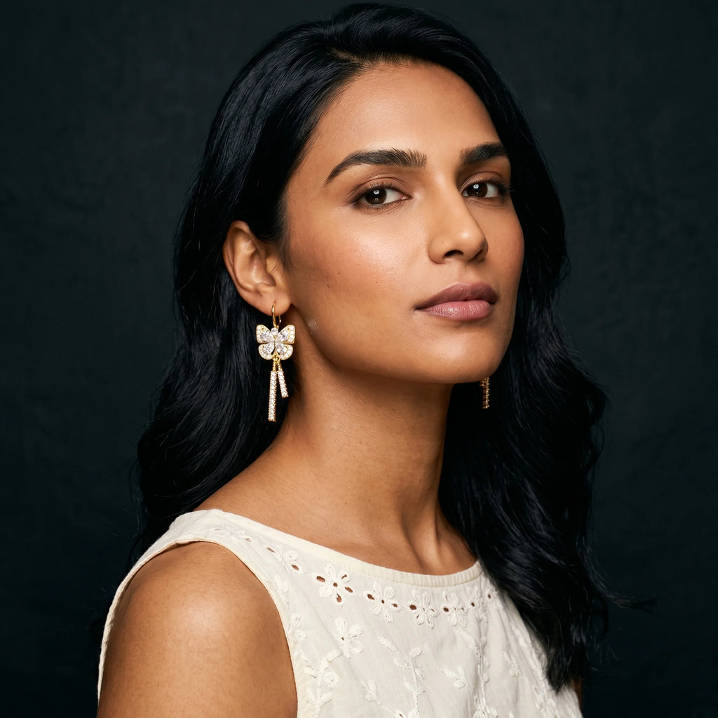 Mira gold butterfly earrings worn with cream eyelet top — soft natural light portrait
