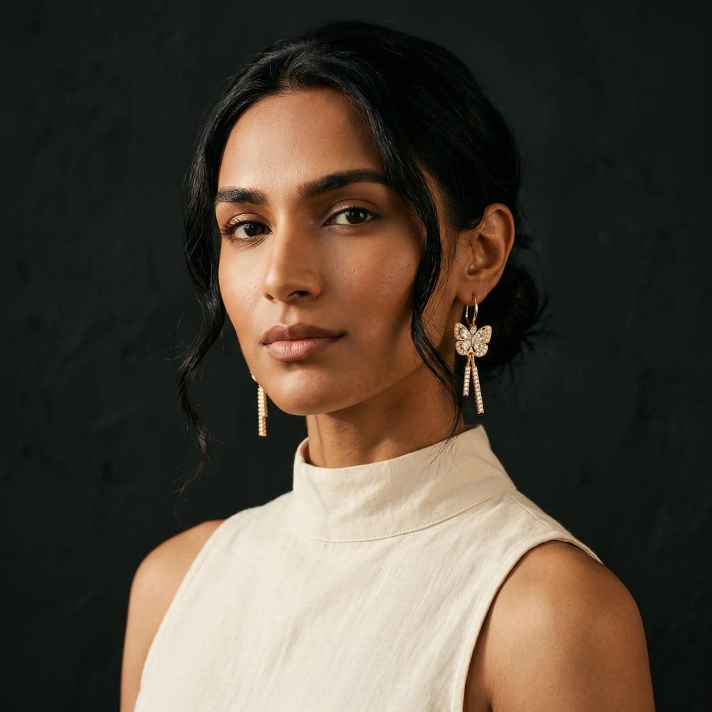 Mira gold pavé butterfly earrings worn with cream high-neck top — three-quarter turn