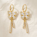 Mira gold butterfly drop earrings with pavé rhinestone wings and tassel drops on cream linen — Aurum & Isle