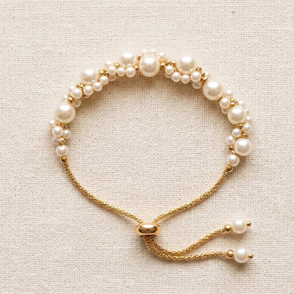 Muktaa pearl cluster bracelet with slider closure and pearl-tipped tassel ends on cream linen — Aurum & Isle