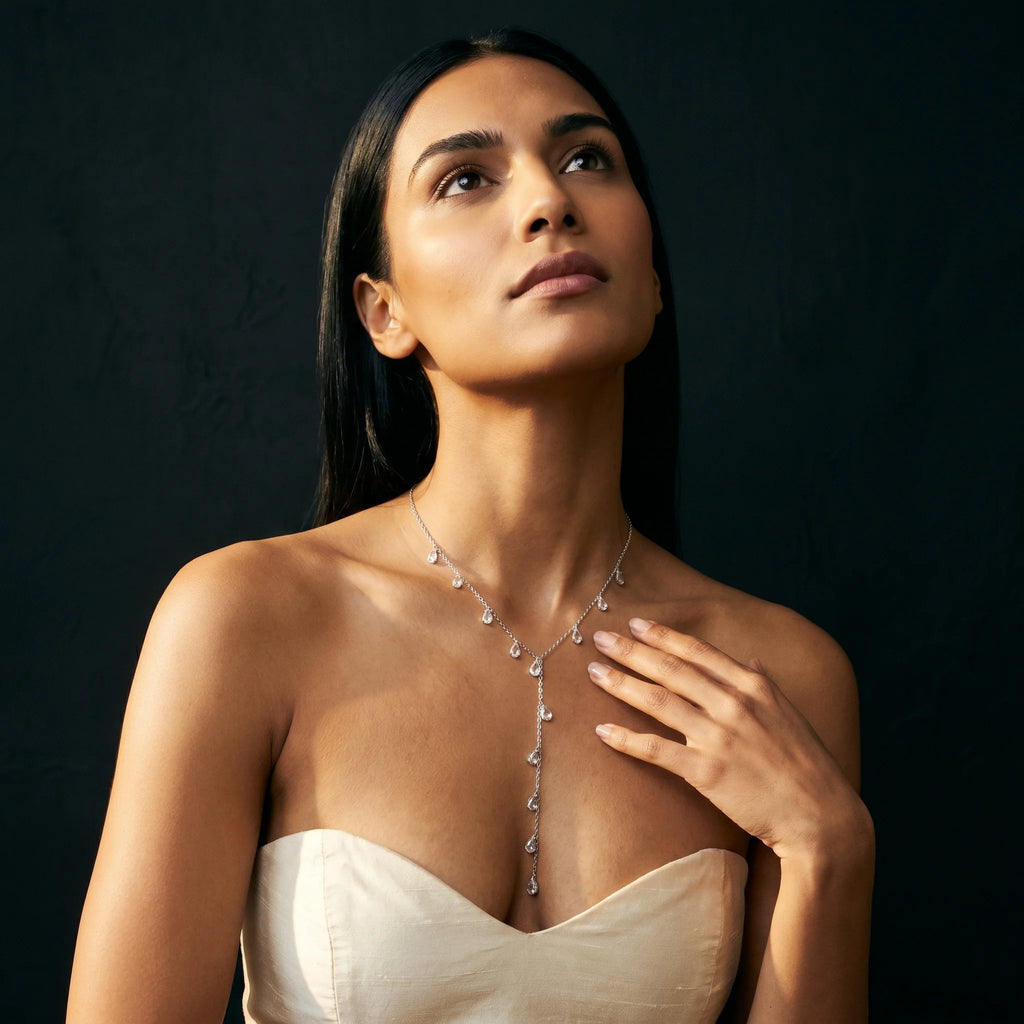 Nira silver teardrop Y-necklace with hand resting at collarbone — eyes-up dreamy frame