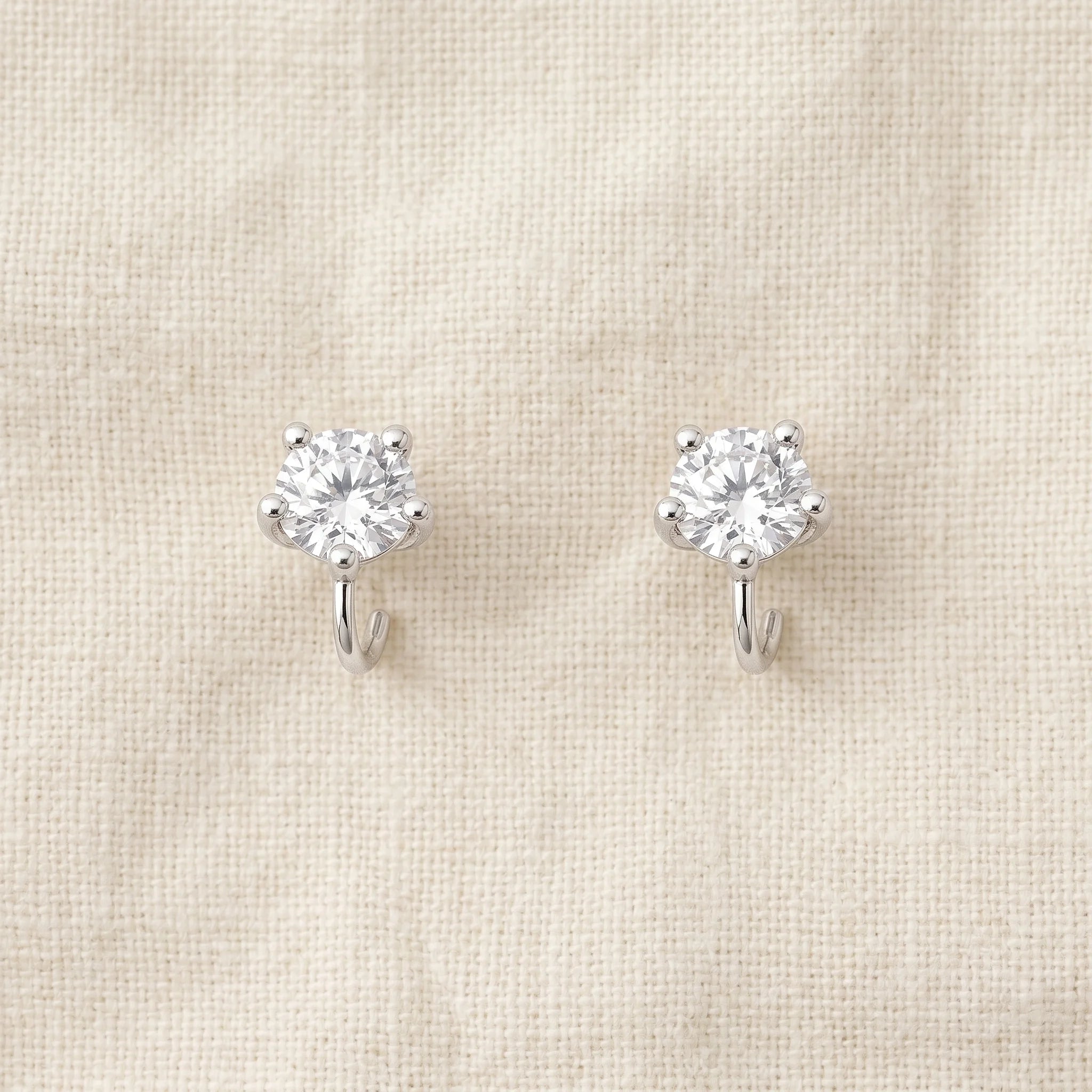 Tara silver-prong cubic zirconia solitaire stud earrings on cream linen — Aurum & Isle